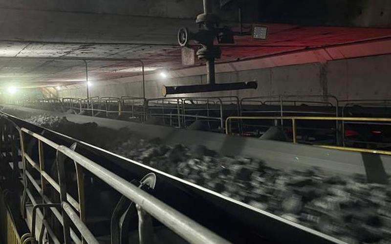 Belt loaded with coal in an enclosed conveyor gallery with red lighting