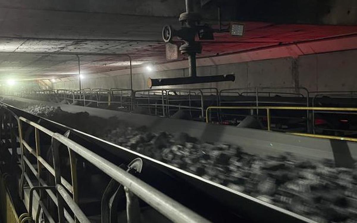 Belt loaded with coal in an enclosed gallery with red lighting